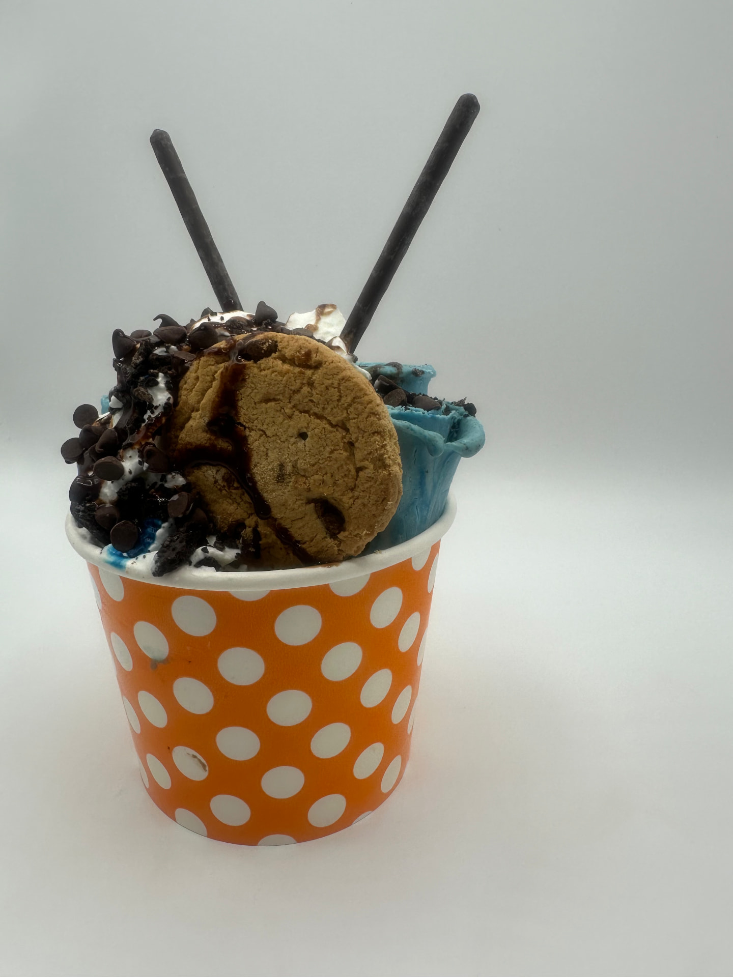 Cookie Monster rolled ice cream in an orange polka-dot cup topped with a chocolate chip cookie and chocolate chips